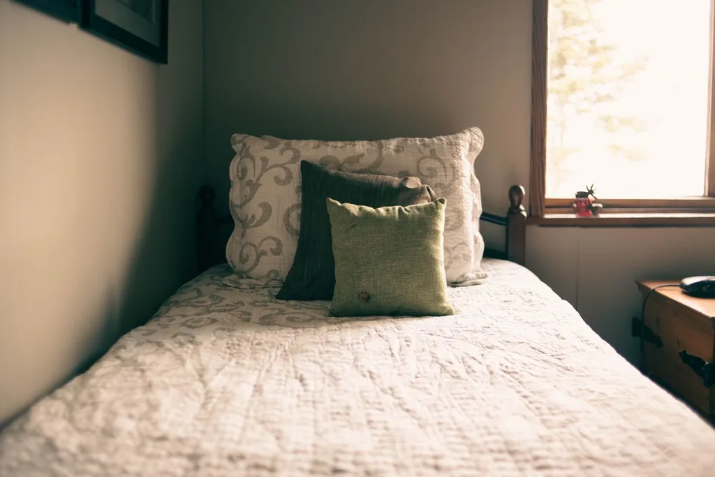 Un lit et ses coussins près d’une fenêtre, photographie d’intérieur